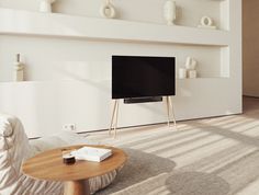 a flat screen tv sitting on top of a wooden table in front of a white wall