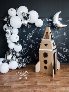 a cardboard rocket ship next to some balloons