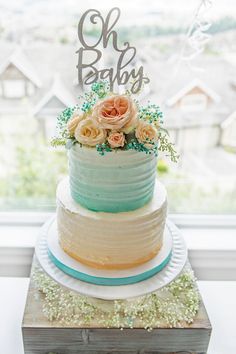 a multi layer cake with flowers on top and the words oh baby spelled in cursive