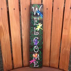 a painted sign sitting on top of a wooden bench next to a fence with dragonflies