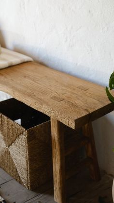 a wooden bench sitting next to a plant in a vase on top of a table