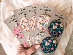 four coasters with floral designs on them in front of a woman's hand