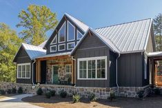 a gray house with two windows and a metal roof is shown in the foreground