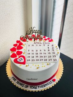 a white cake with red and yellow hearts on it that says happy anniversary to the two years of togetherness