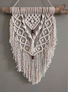 a white macrame hanging on a wall next to a piece of driftwood