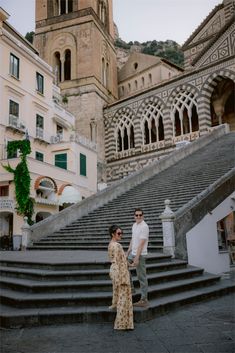 a man and woman standing on steps in front of an old building