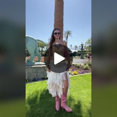 a woman wearing pink boots standing in front of a palm tree with her hands on her hips