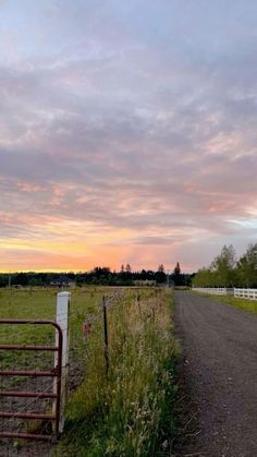 an empty country road near a fence at sunset