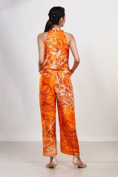 Orange halter jumpsuit in russian silk base with floral, abstract pattern and pleats detailing.
Components: 1
Type Of Work: Floral, Abstract
Neckline: Round
Sleeve Type: Sleeveless
Fabric: Russian silk
Color: Orange
Other Details: 
Tassel, pleats detailing
Closure: Zipper
Occasion: Party - Aza Fashions Sleeveless Silk Jumpsuits And Rompers For Summer, Sleeveless Silk Jumpsuit For Summer, Silk Jumpsuits And Rompers For Summer, Festive Orange Palazzo Set With Printed Motifs, Luxury Orange Embroidered Palazzo Set, Sleeveless Silk Summer Jumpsuit, Casual Orange Jumpsuit With Floral Print, Orange Floral Print Summer Jumpsuit, Floral Abstract Pattern