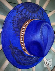 WEARING THE BLUES FEDORA Wide brim. Blue color custom hand burn fedora. Handmade. Adjustable inside ribbon. Comes as pictured. Item Details: Branded Wide Brim HatsEach hat is hand burned for a custom branded design, because of that each order will vary slightly. Hat band is included in the order. Please feel free to message me with any customization requests. These are quite literally completely customizable. Due to the custom nature of our hats, all purchases are nonreturnable and nonrefundable Blue Fedora With Curved Brim For Festival, Blue Flat Brim Fedora For Festivals, Blue Fedora Felt Hat For Festivals, Blue Wide Brim Felt Hat For Festivals, Custom Handmade Blue Hat Band, Custom Blue Wide Brim Hat, Custom Blue Flat Brim Hat, Handmade Blue Hat Bands With Curved Brim, Blue Artisan Fedora With Adjustable Fit