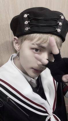 a young boy wearing a black and white outfit with his hands on his head, posing for the camera