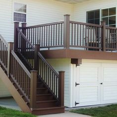 a brown stair case next to a white building with two garage doors and a bicycle on the balcony