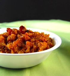 a white bowl filled with food sitting on top of a green tablecloth covered table