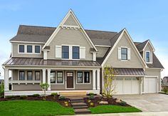 a large gray house with white trim on the front and side windows, two car garages