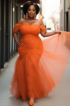 a woman in an orange dress is standing on the sidewalk with her arms spread out