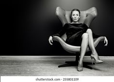 a woman sitting in a chair with her legs crossed and wearing high heeled shoes