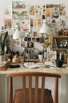 a wooden chair sitting in front of a desk covered with pictures and plants on the wall