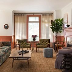 a living room with couches, chairs and a fire place in front of a window