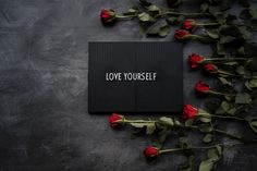 Love yourself written on a card with roses next to it