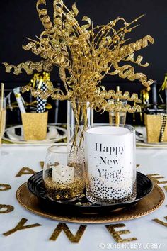 a black and gold new year's eve table setting with glasses, vases and napkins