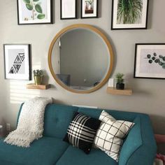 a living room with a blue couch and pictures on the wall above it, along with a round mirror