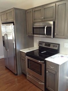 an empty kitchen with stainless steel appliances and wood flooring in the middle of it