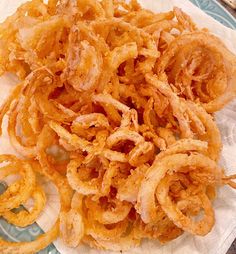 fried onion rings are on a plate with napkins