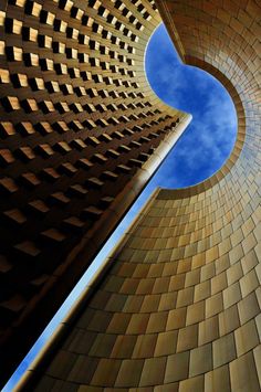 looking up at the side of a brick building with a blue sky in the background