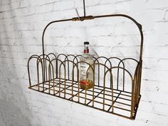 a bottle of alcohol is hanging from a metal rack on a white brick wall,