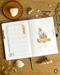 an open planner book with shells and seashells around it on a wooden table