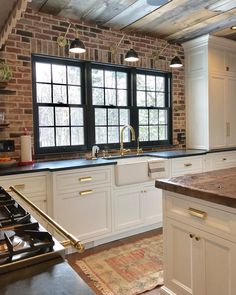 a kitchen with an oven, sink and stove top in front of a brick wall