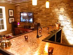 a room with a bar, television and several glasses sitting on the counter in front of it