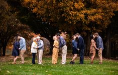 a group of people standing next to each other on a lush green field with trees in the background