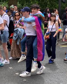 two people hugging each other in the middle of a street with many people standing around