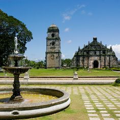 an old building with a fountain in the foreground and a clock tower in the background