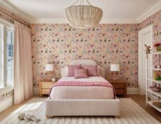 a bedroom decorated in pink and white with floral wallpaper, a chandelier and bed