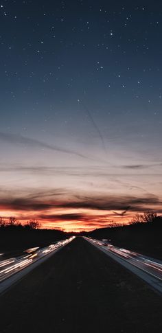 the night sky is lit up with stars and streaks as cars drive down an empty highway