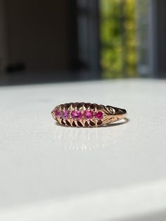 An antique ruby boat style ring, set on 9ct gold with decorative shoulders and setting.   The ring has lovely clear hallmarks for Birmingham and dated to 1912 - making it 112 years old. In very good condition.  The ring has a 5 pink-ish red ruby stones in a 'boat ring' style setting and with decorative shoulders.   Current size R. Approximate weight is 2.8g. Please note we would recommend that this ring is not significantly resized, to avoid damage to the hallmarks and overall shape and design o Antique Hallmarked Ruby Ring, Antique 14k Stamped Ruby Ring, Victorian 14k Gold Ruby Ring In Red, Victorian Ruby Ring In 14k Gold, Antique Pink Ruby Ring With Rose Cut Diamonds, Antique Pink Ruby Ring, Pink Hallmarked Victorian Ruby Ring, Victorian Pink Hallmarked Ruby Ring, Pink Victorian Hallmarked Ruby Ring