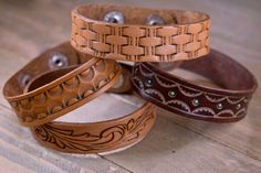 four leather bracelets sitting on top of a wooden table