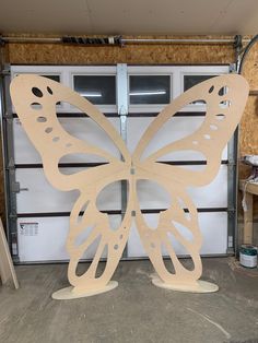 a large wooden butterfly sitting in front of a garage door