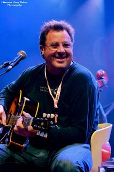 a man sitting in front of a microphone playing a guitar