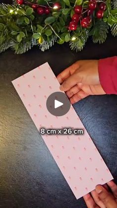 someone is making a christmas card with paper and glue on the edge, while another person's hands are holding it