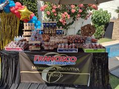 a table covered in balloons and desserts next to a swimming pool at a party