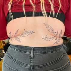 the back of a woman's stomach with leaves tattooed on her lower body and bottom