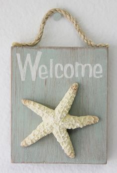 a welcome sign with a starfish hanging from it's side on a wall