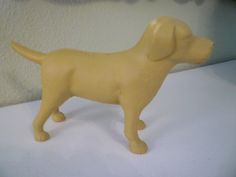 a yellow dog figurine is standing on a white countertop next to a wall