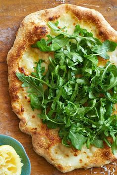 a pizza topped with greens on top of a wooden table