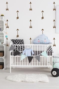 a baby's room with an arrow wall decal and white crib bedding