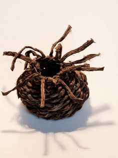 a close up of a small basket made out of sticks and twigs on a white surface