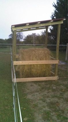 a hay bale in a fenced off area next to a wooden structure with metal bars on the sides